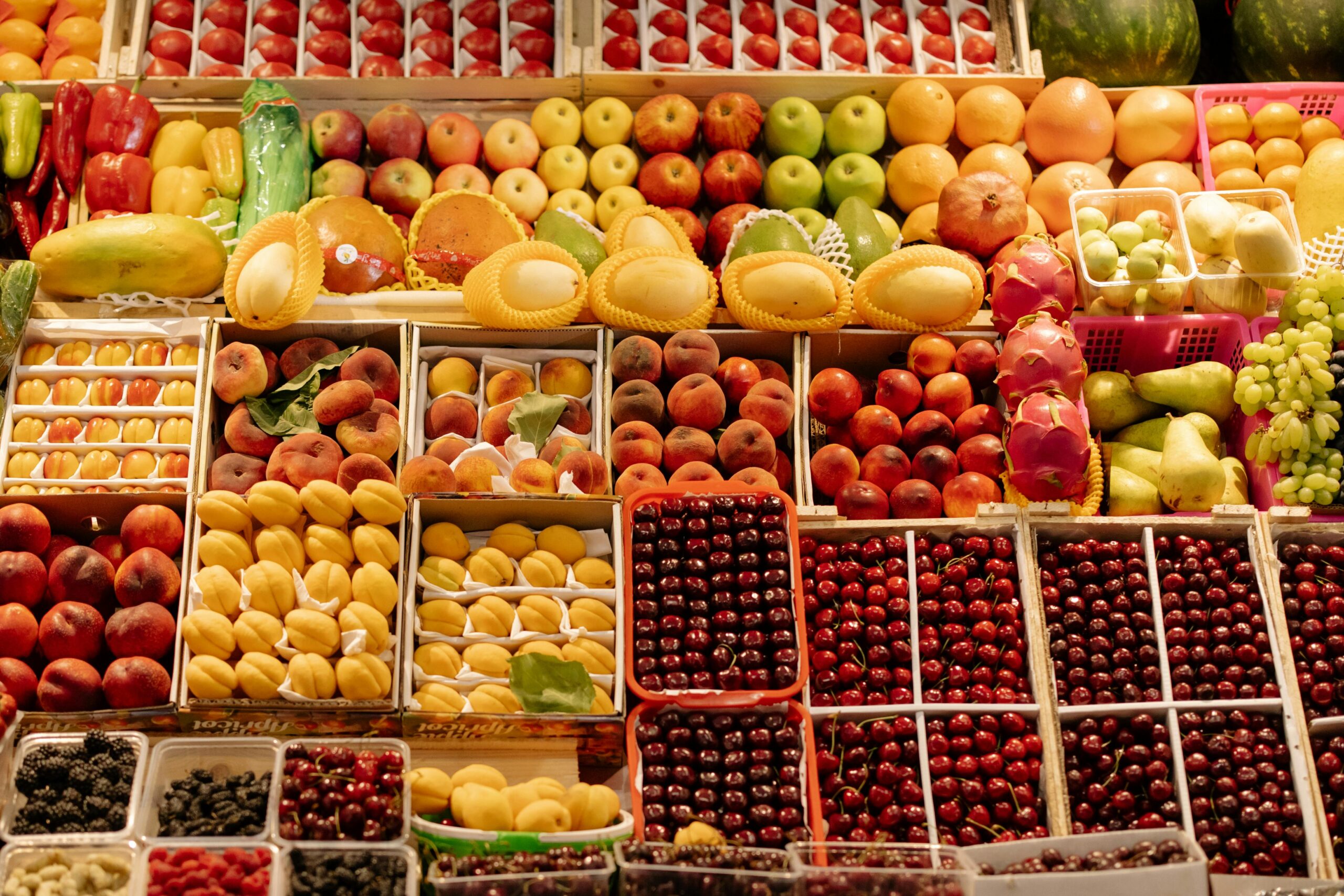 Colorful arrangement of fresh fruits at a bustling market stall, showcasing seasonal produce.